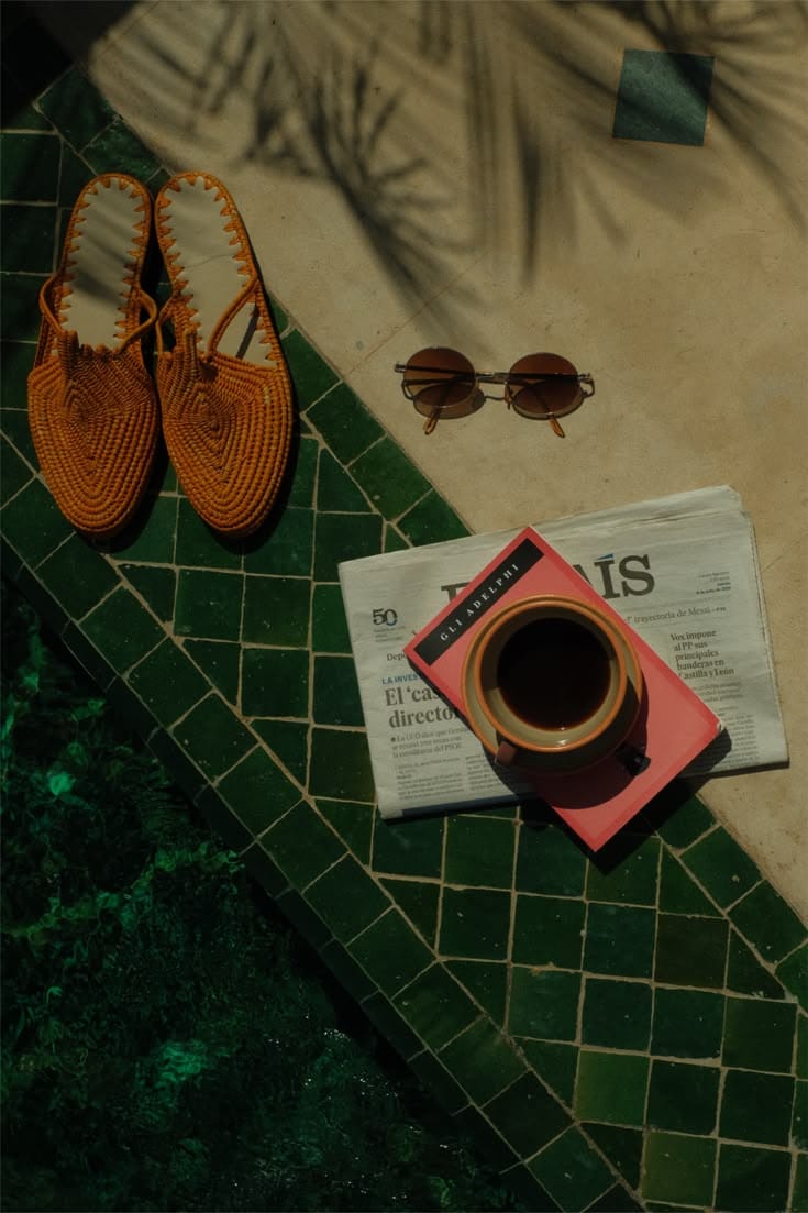 Woven sandals, sunglasses and coffee on green tiles